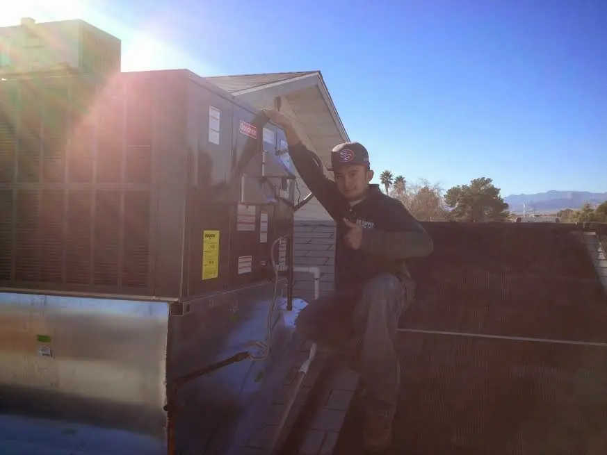 HVAC technician performing Air Duct Cleaning on a rooftop unit in Bay City